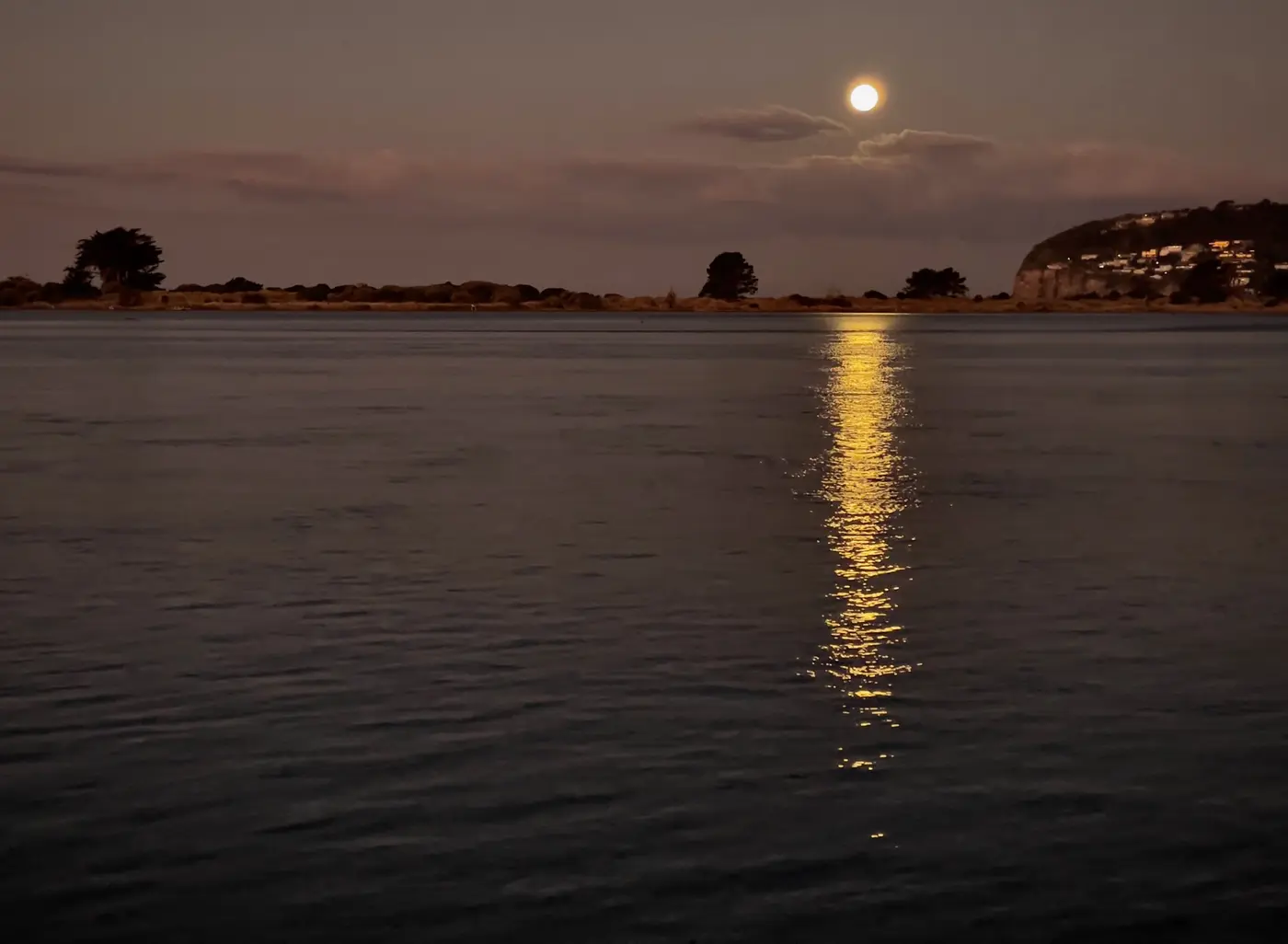 A full moon casting a golden path across dark, still water